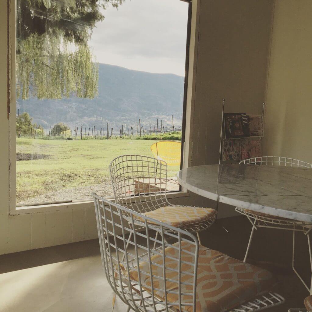 The view of the vineyard and Skaha lake from the dining room, with Saaranen tulip table and Bertoia chairs.