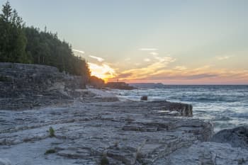 ocean waves crashing on rocky shore during sunrise